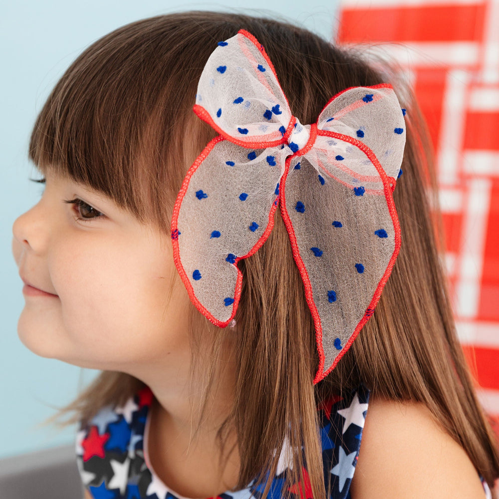little girl wearing sheer red, white and blue 4th of july hair bow