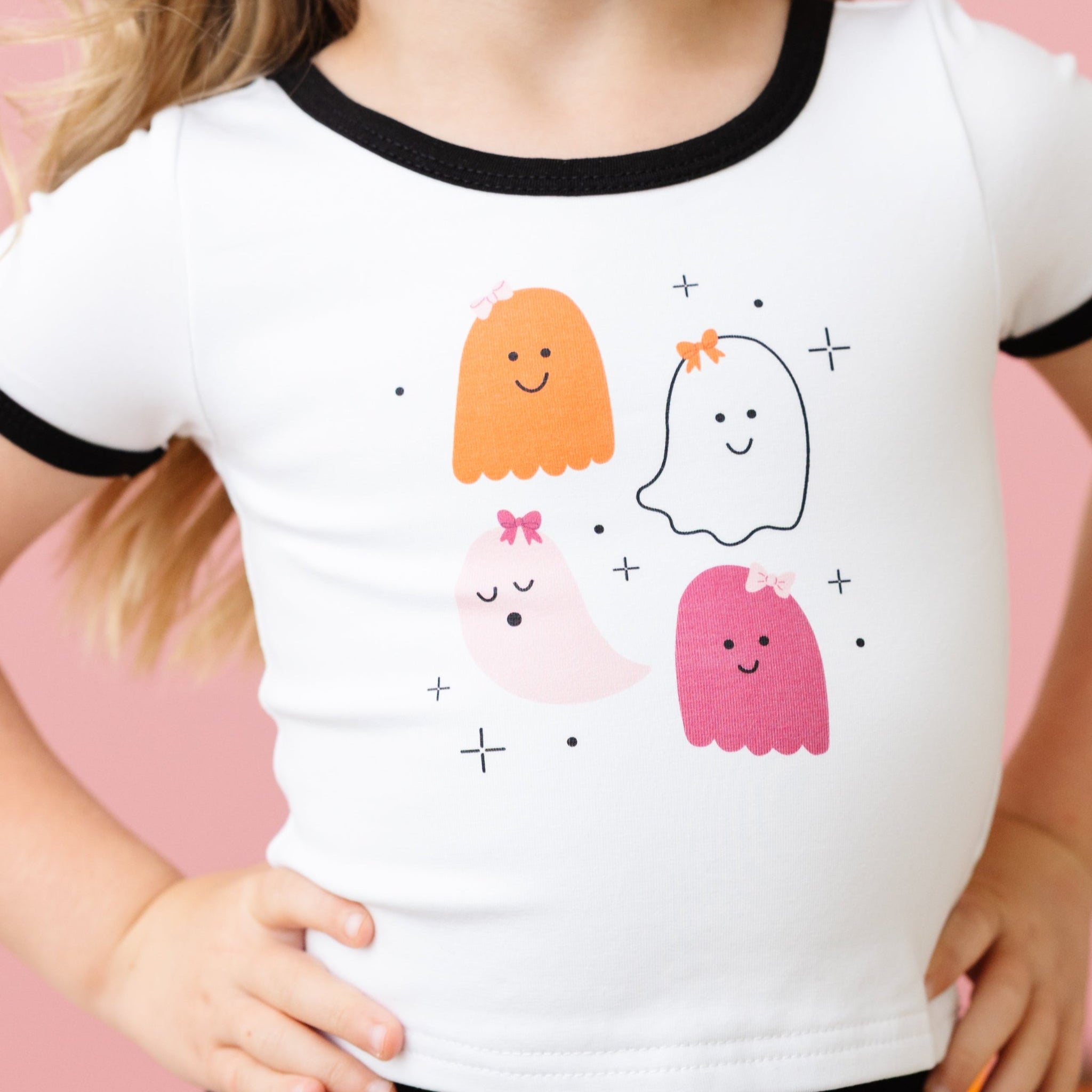 closeup of little girl in white cotton spandex blend fitted top with black binding and Halloween design with four ghosts in bows