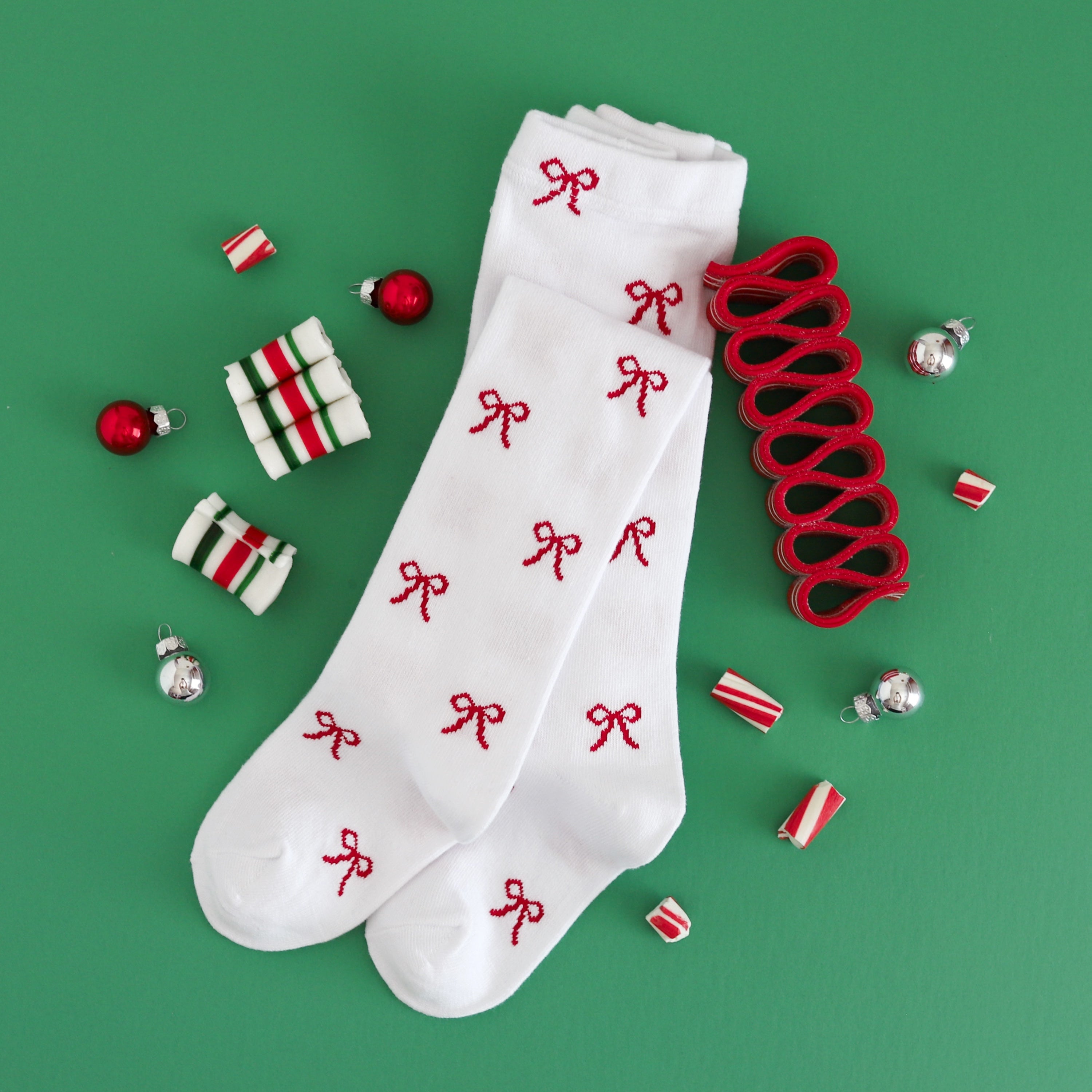 flat lay photo of girls' white knit tights with red bow design for Christmas