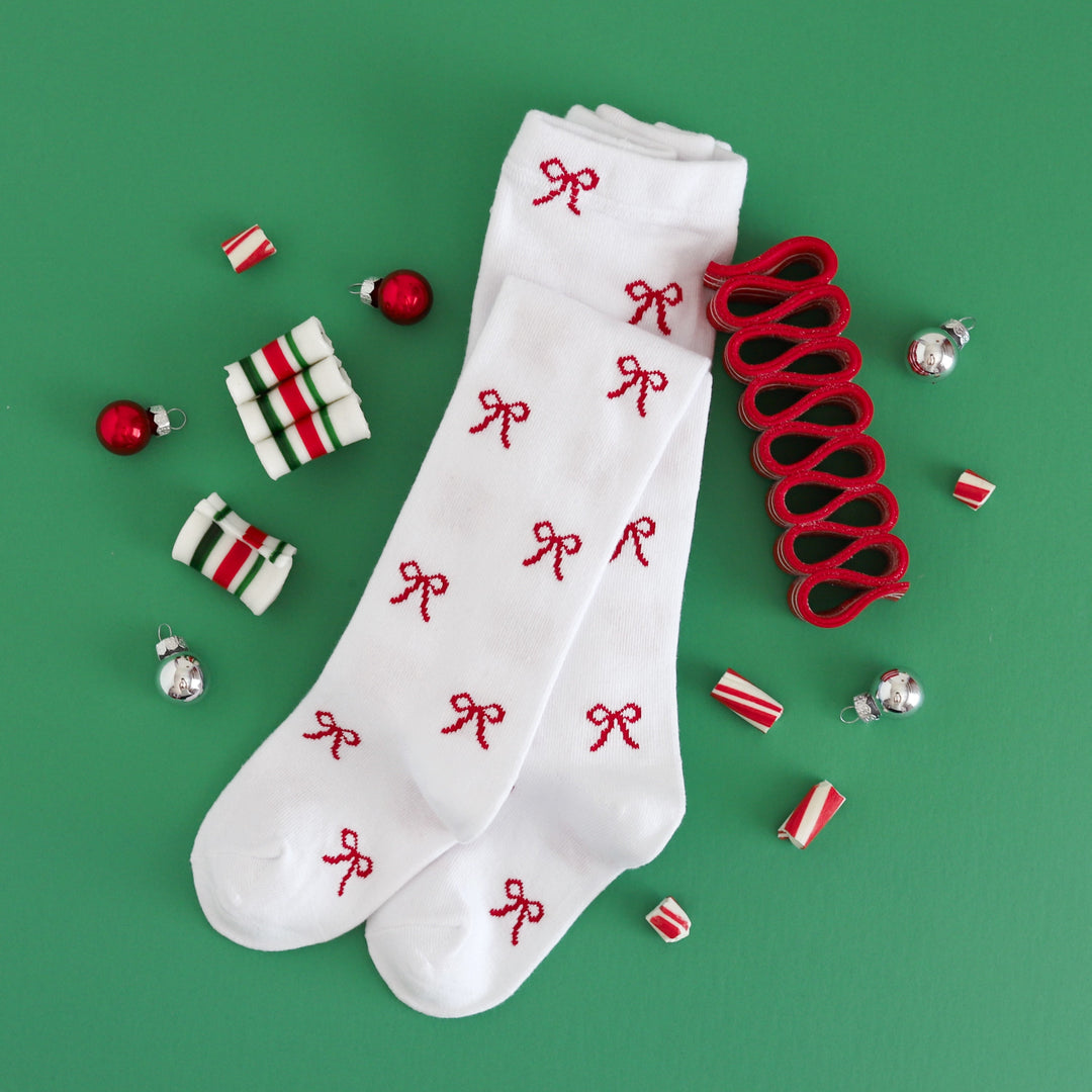 flat lay photo of girls' white knit tights with red bow design for Christmas