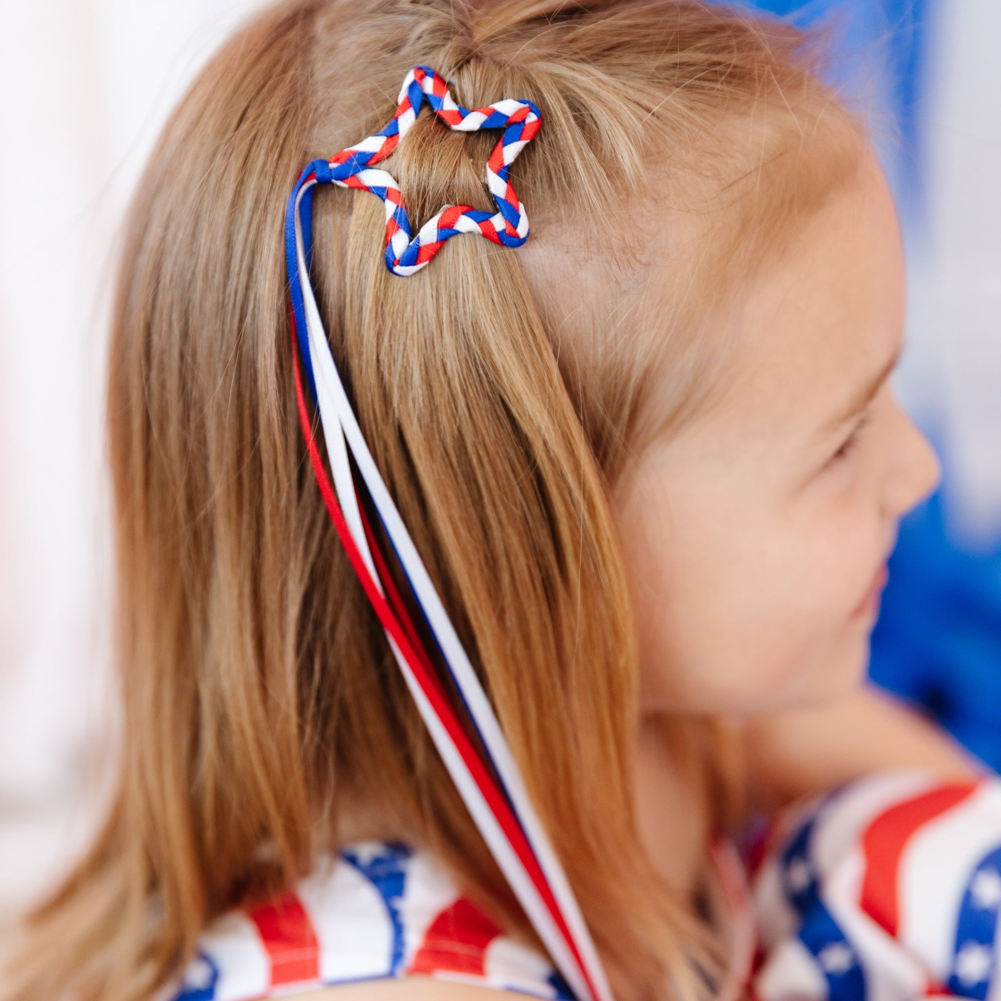 girl wearing star shaped ribbon hair clip with braided red, white and blue star for fourth of july