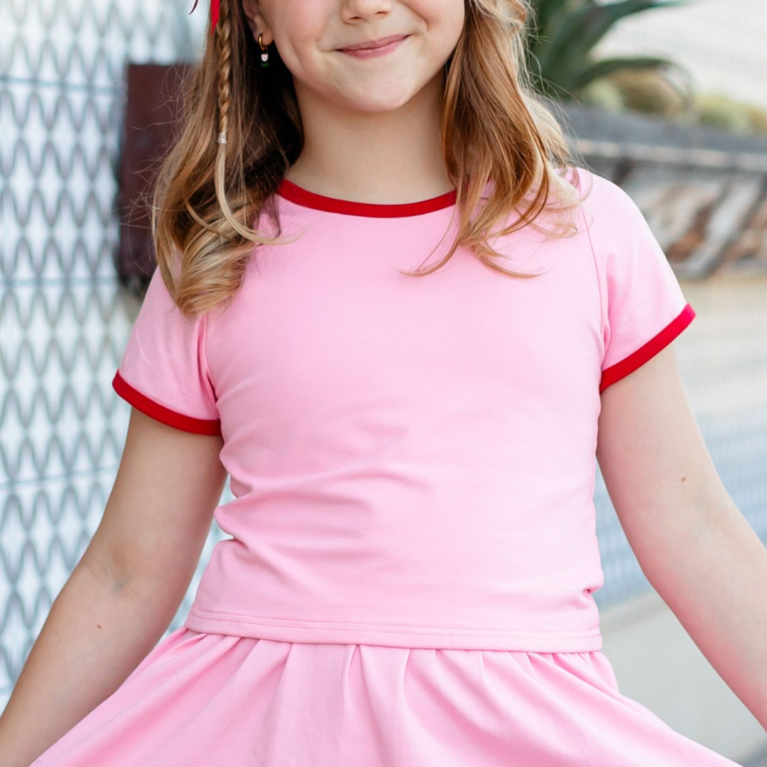 closeup of girl's pink t-shirt with red trim for summer skirt set