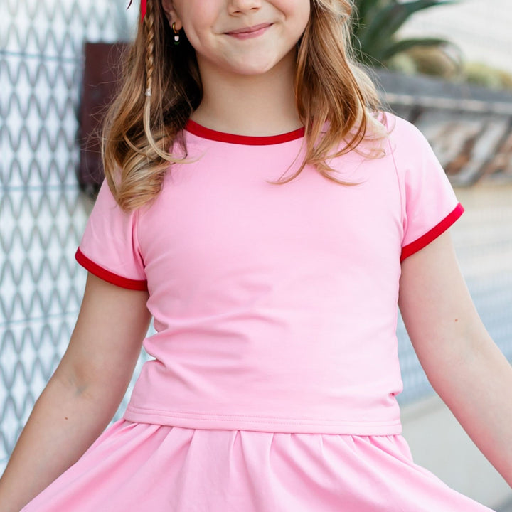 closeup of girl's pink t-shirt with red trim for summer skirt set