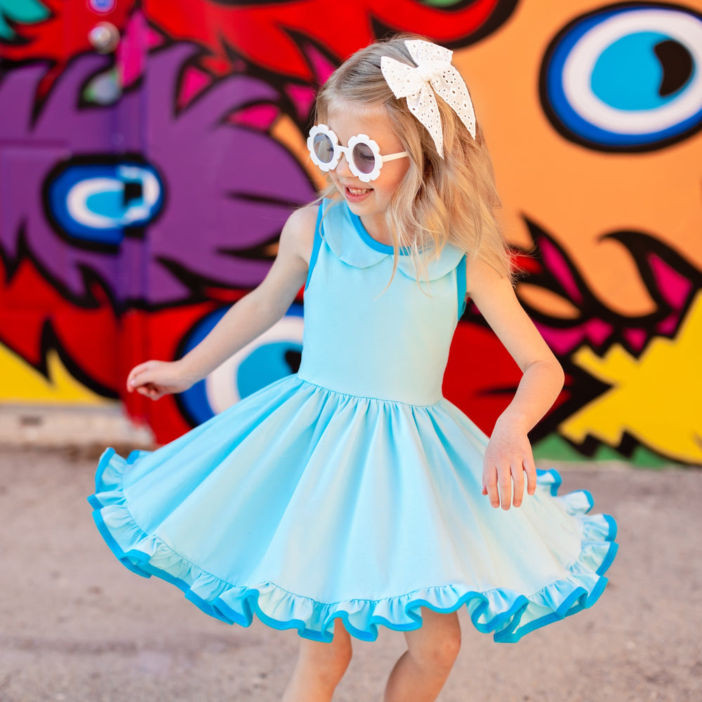 little girl wearing sunglasses twirling in bright aqua blue summer dress