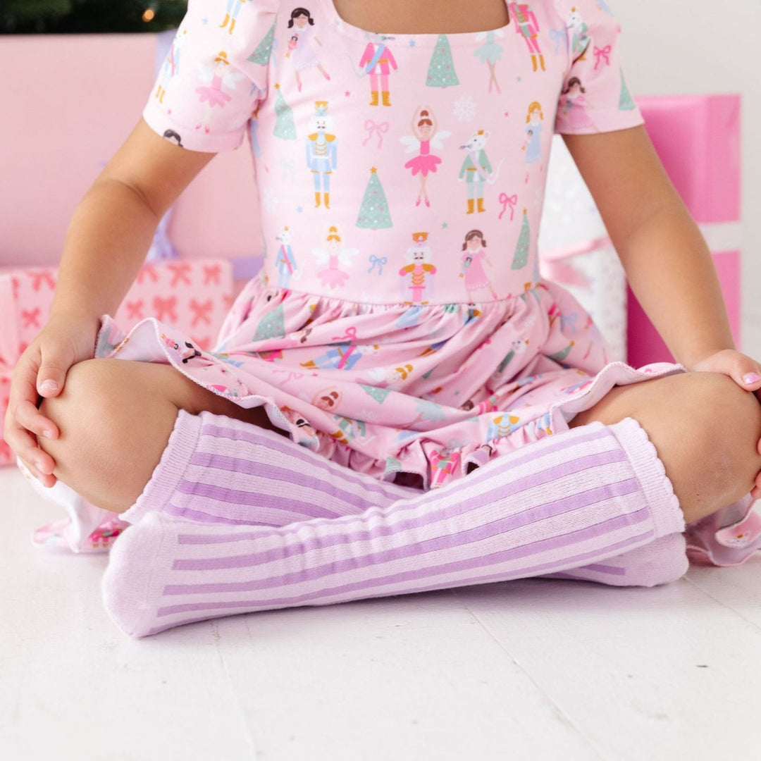 girl wearing pastel purple vertical stripe socks with pink nutcracker christmas dress