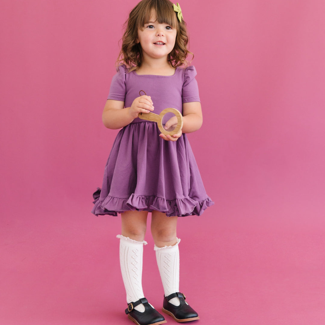 little girl in purple twirl dress and ivory cream knee high socks