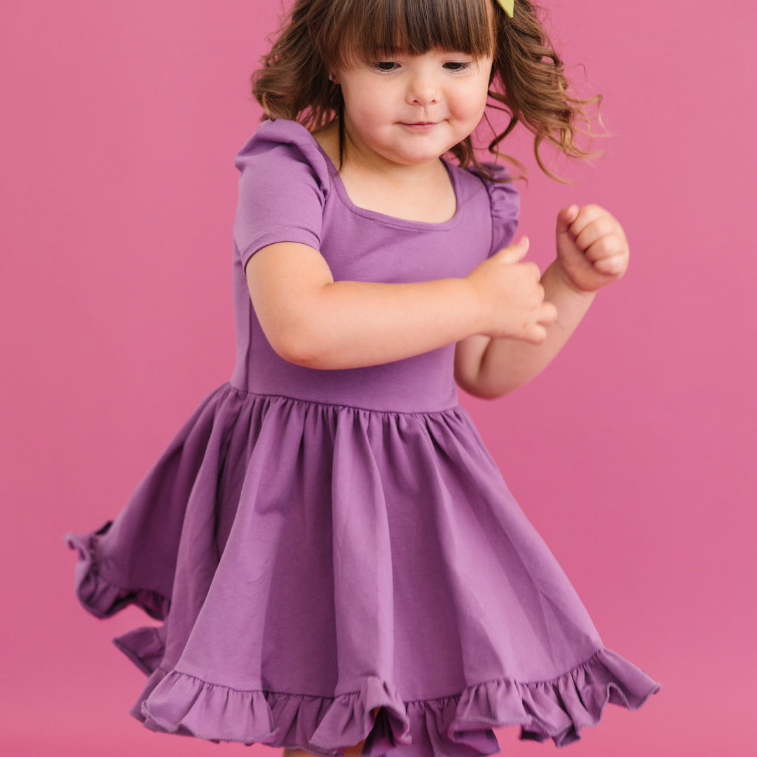 little girl twirling in purple cotton dress