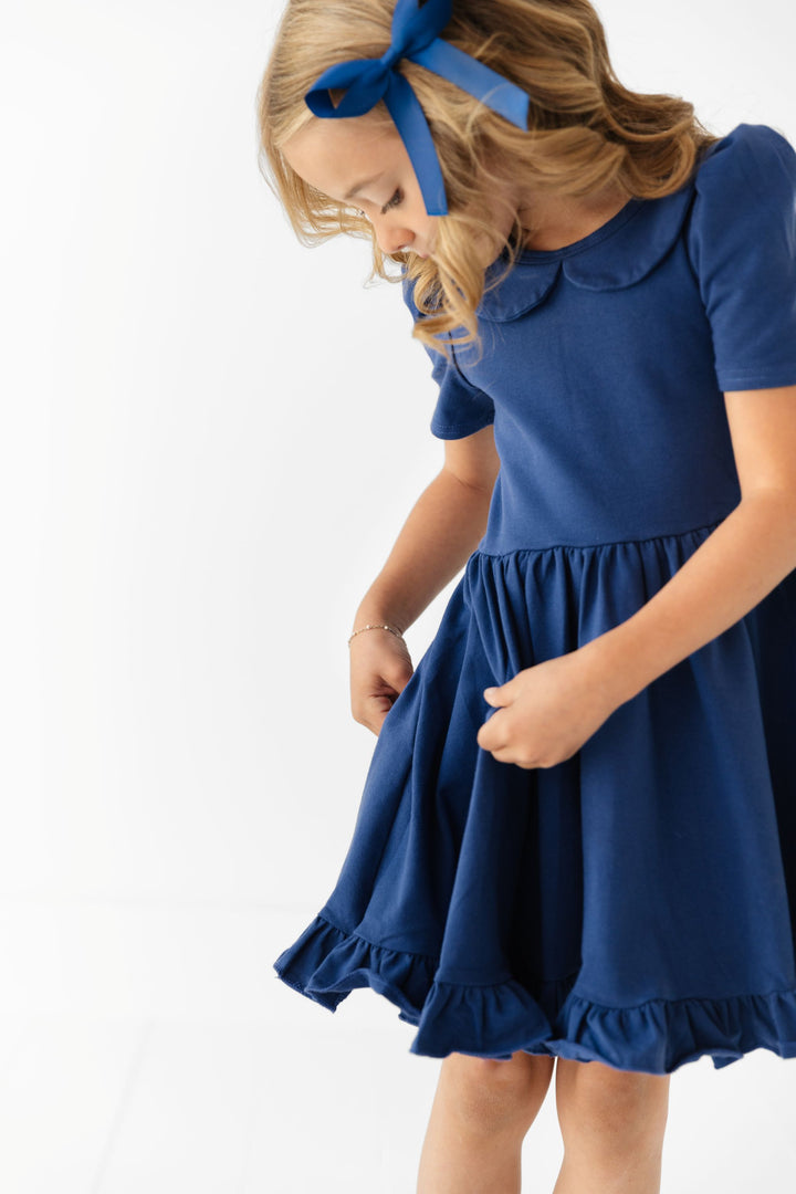 little girl in navy blue cotton twirl dress with collar and matching satin bow for school uniform