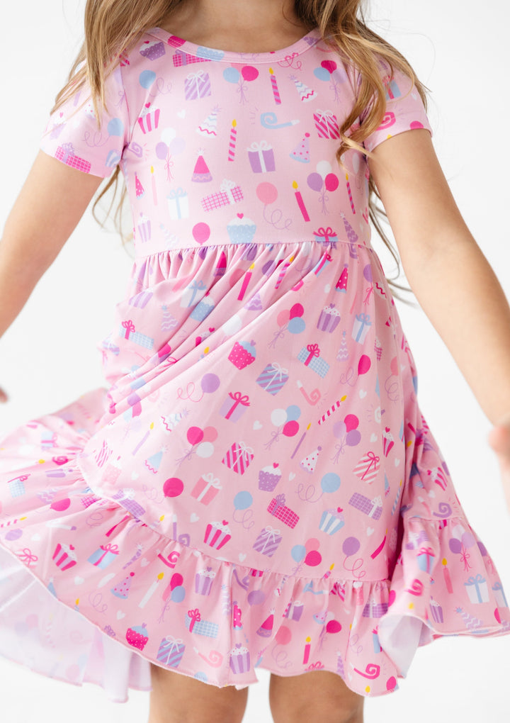 detail picture of girl wearing pink twirl dress with birthday items on it