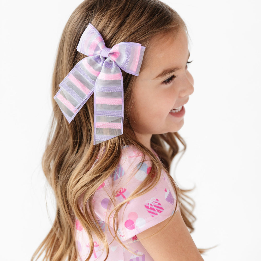 girl wearing pink and purple striped double bow and matching pink birthday dress