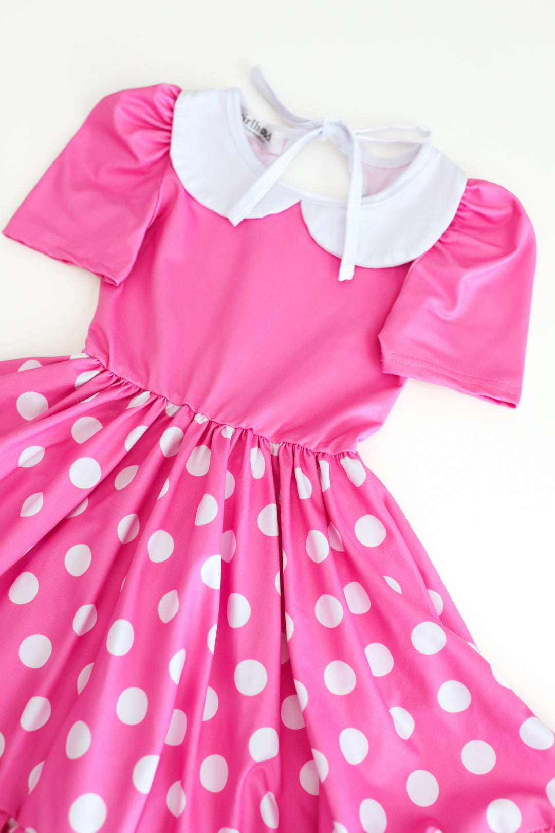 detail photo of girls' short sleeve pink Minnie inspired twirl dress with pink bodice, pink skirt with white polka dots, and white peter pan collar