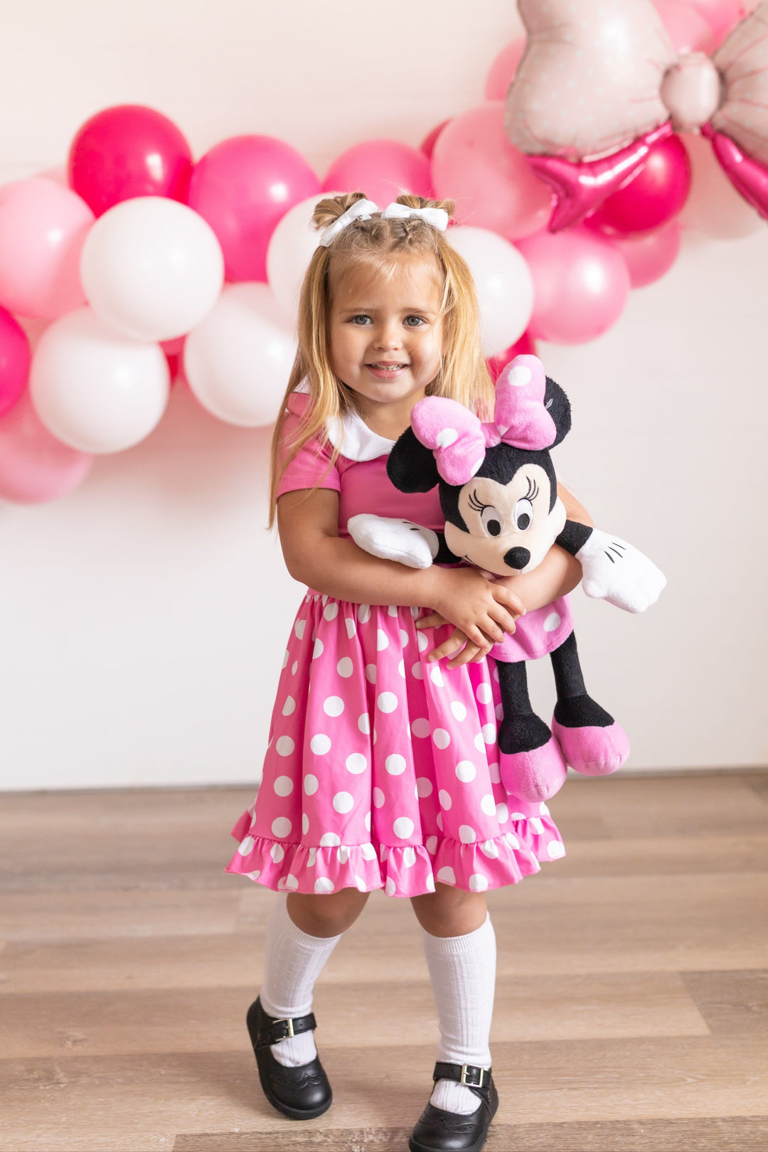 girl at party in pink minnie mouse character twirl dress and white cable knit knee highs with white pigtail bows