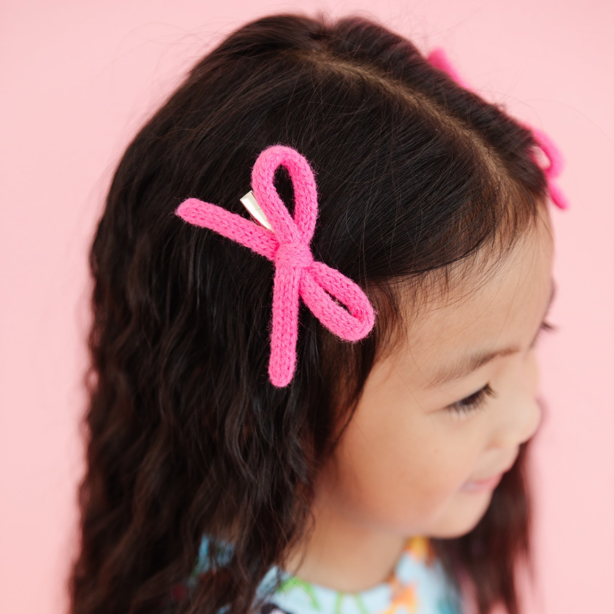 little girl in bright pink knit pigtail bows on clips