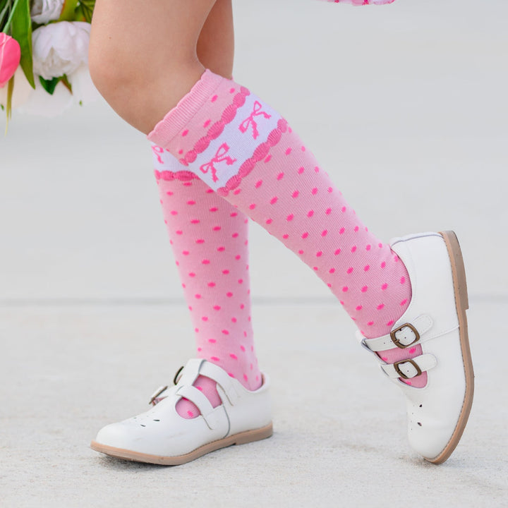 little girl in pink wallpaper print spring twirl dress and matching pink scalloped knee highs with polka dots and printed bows