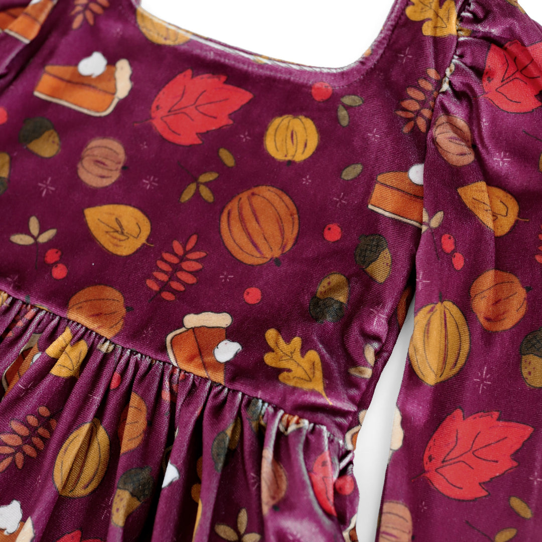 close up of plum velvet twirl dress bodice with pumpkin, fall leaf and pumpkin pie print