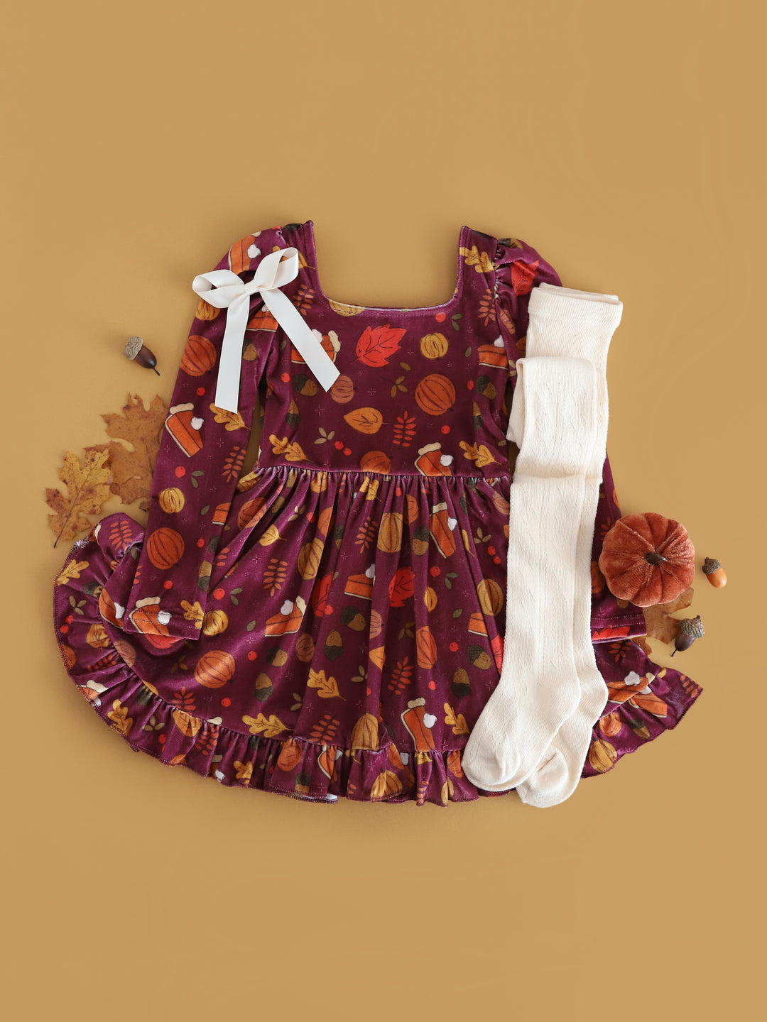 flat lay styled photo for plum velvet long sleeve twirl dress with pumpkin, pie and fall leaf print for Thanksgiving