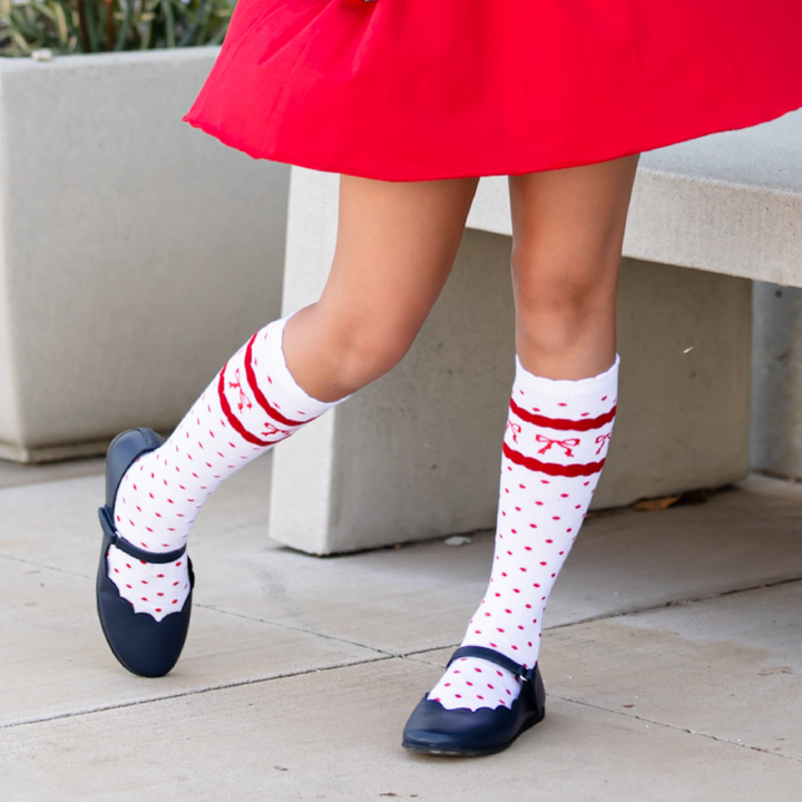 girl wearing scallop trimmed knee highs in white with red dots and red bow print and matching red skort