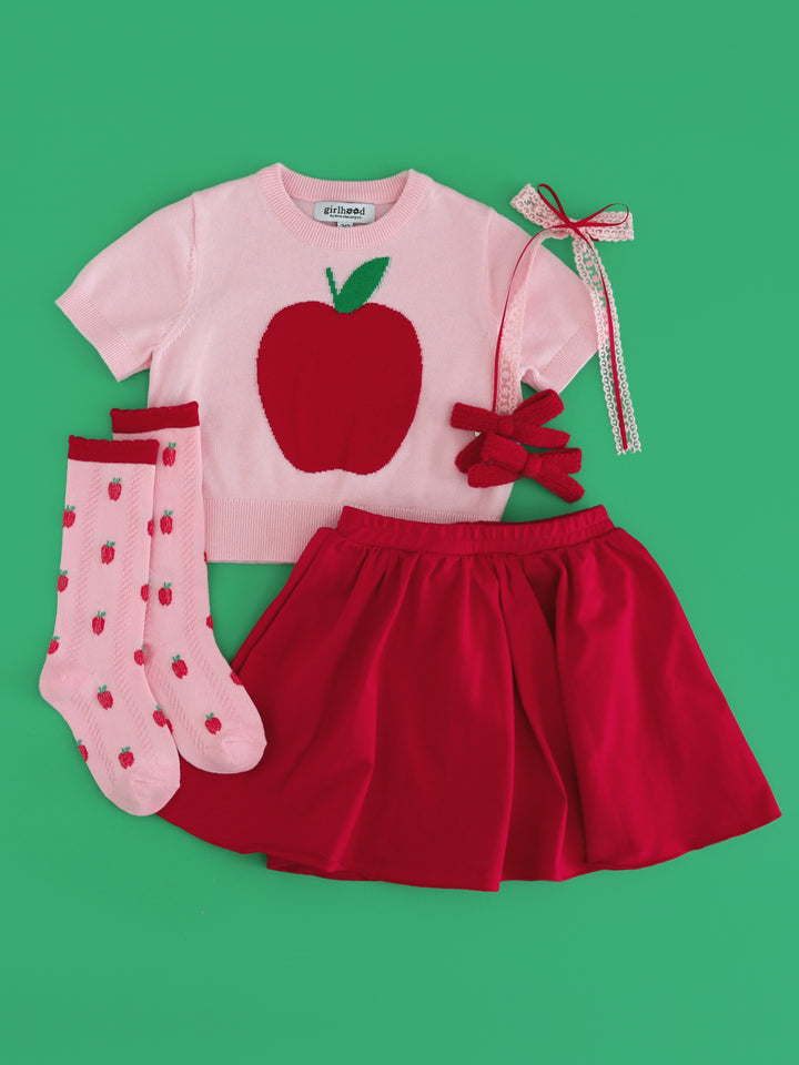 little girl's back to school and apple picking outfit with short sleeve pink sweater with red apple design, red stretchy cotton skirt, matching apple print knee highs and coordinating hair bows