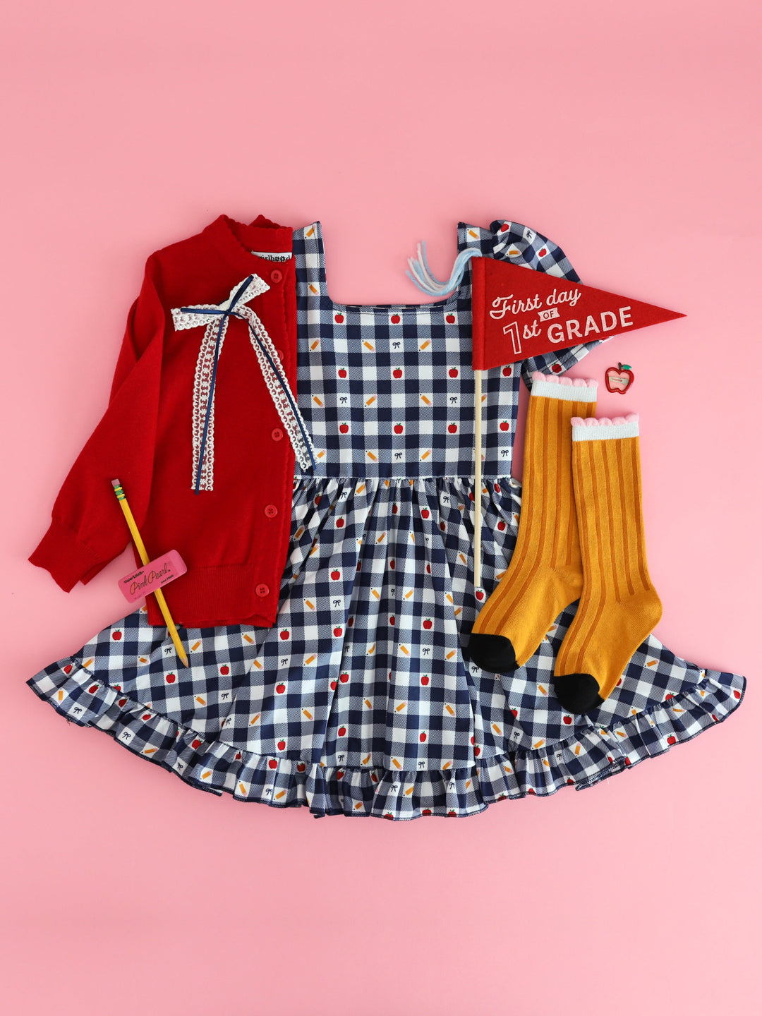 girl's first day of first grade outfit featuring navy and white gingham square neck twirl dress with pencils socks, red cardigan and matching bow
