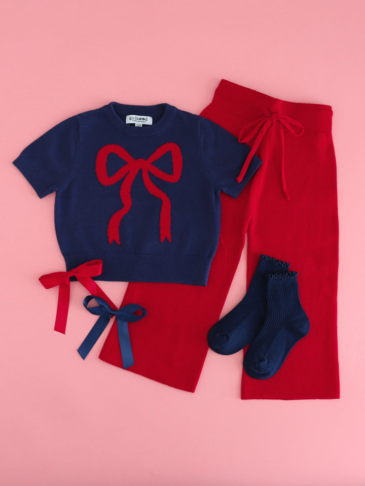 girl's navy short sleeve sweater with red bow design and matching red sweater pants paired with navy midi socks  and matching satin ribbon bows