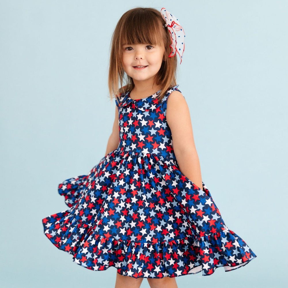 little girl wearing star print 4th of july twirl dress with her hands in the pockets