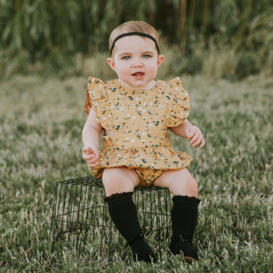 little girl sitting on wire basket with black lace top knee high socks