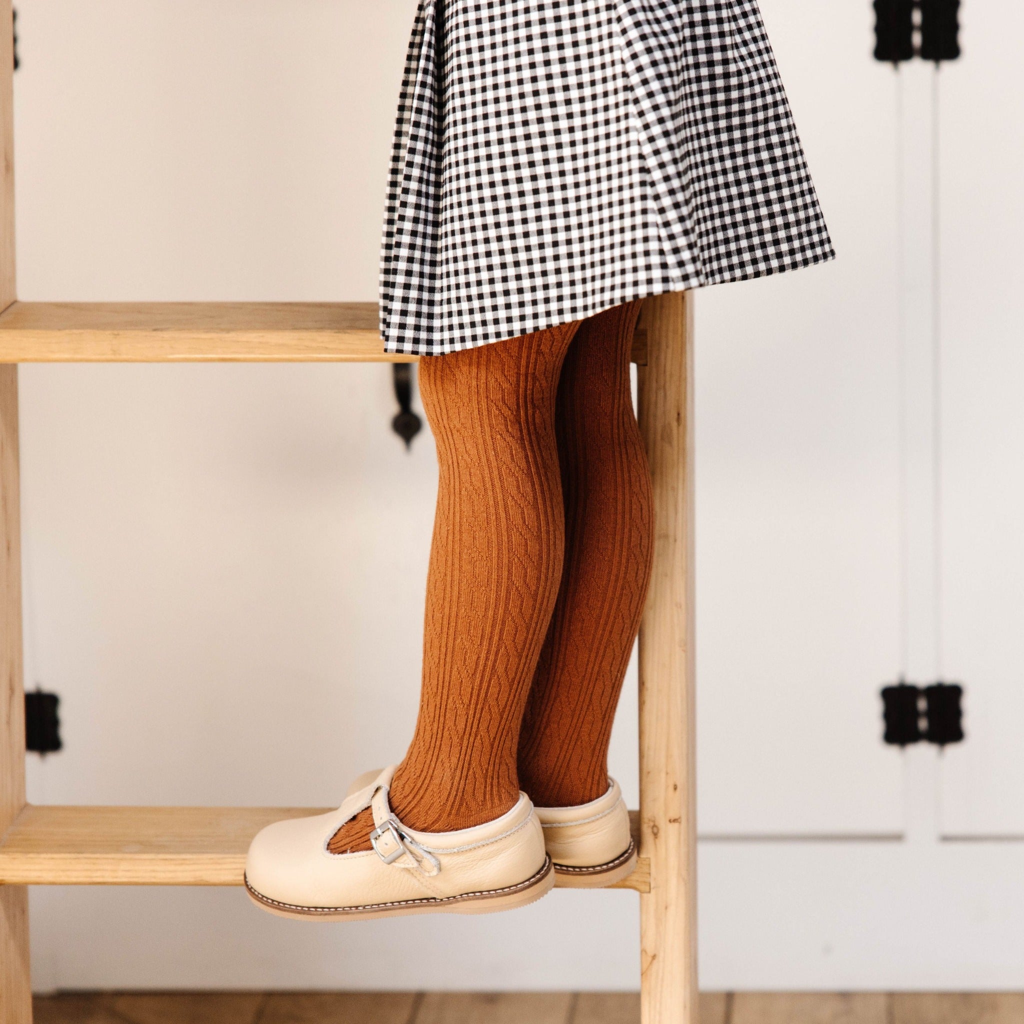 little girl standing on ladder in sugar almond cable knit tights