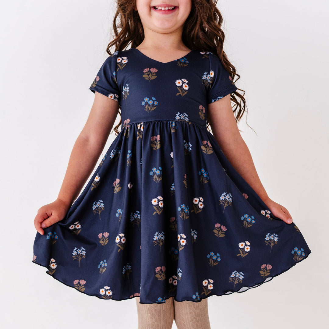 little girl in navy v-neck twirl dress with lettuce trim hem and fall wildflower print
