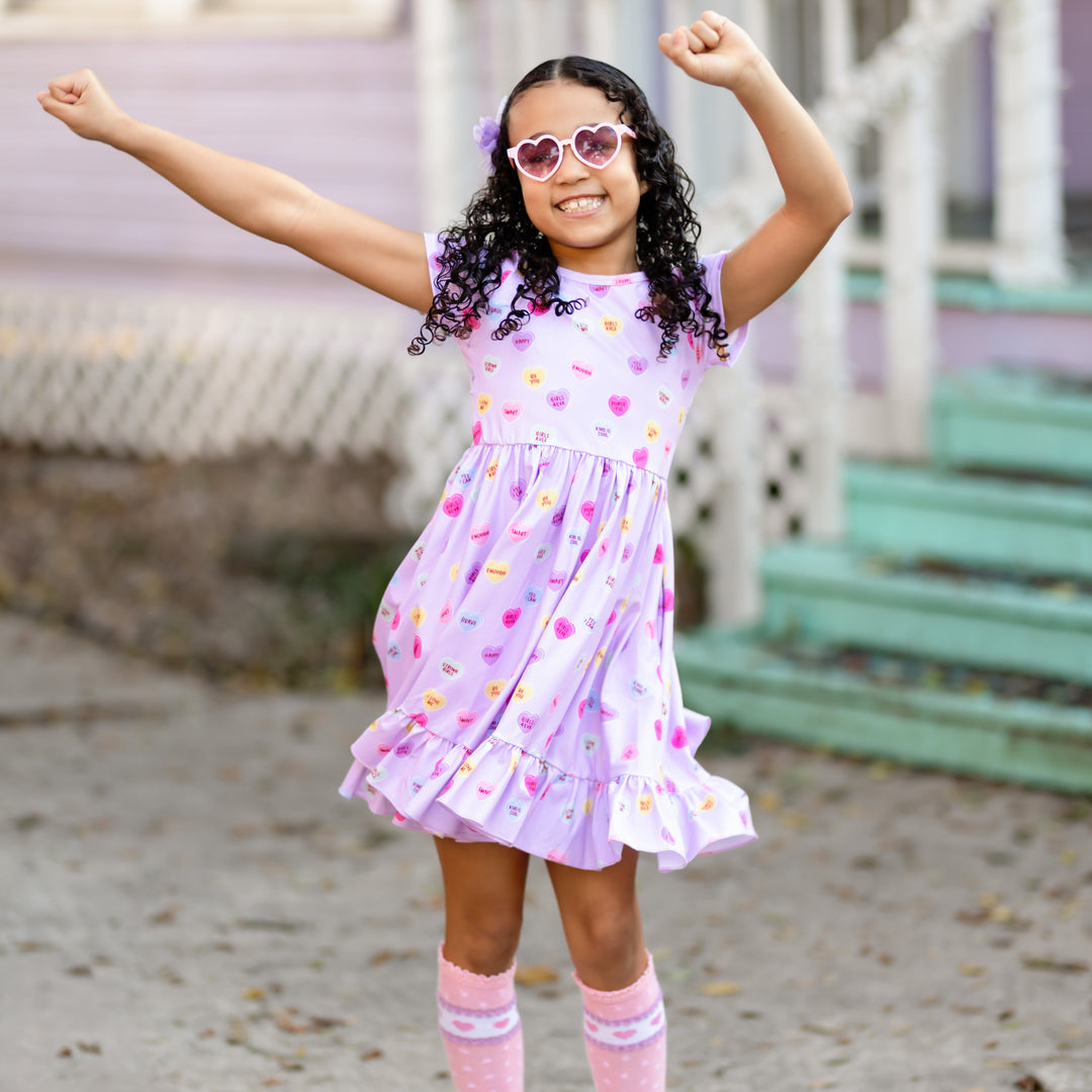 little girl dancing in lavender conversation heart inspired Valentine's dress and matching accessories