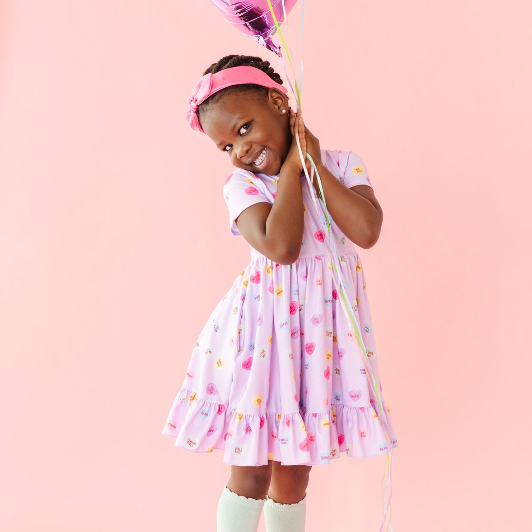 little girl in lavender pastel heart dress with words of affirmation and matching pink satin headband