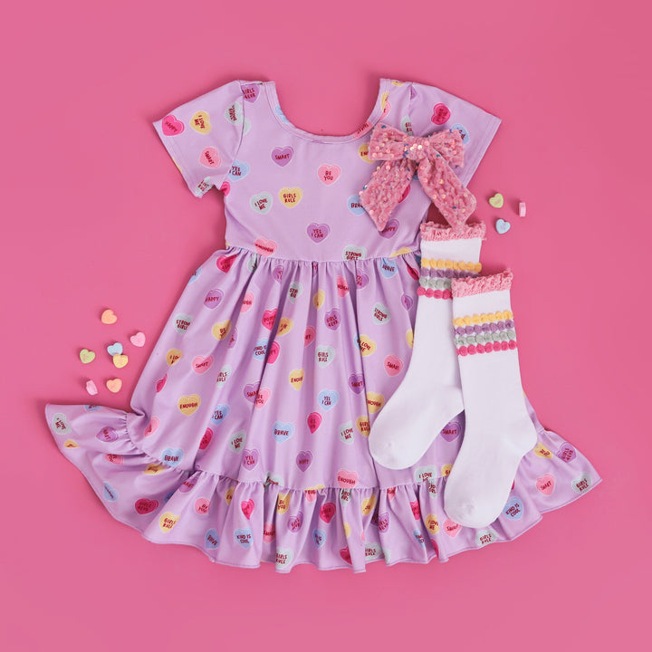 girls conversation heart inspired Valentine's dress with positive phrases, matching pastel stripe socks and pink velvet bow with sequins