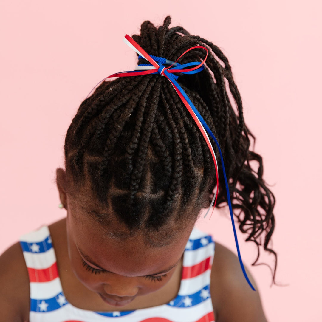 little girl in ponytail with red, white and blue ribbon bow for 4th of July 