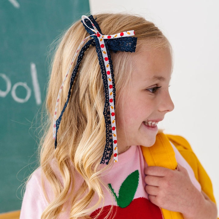 Little girl wearing Back to school hair bow with apples and pencils