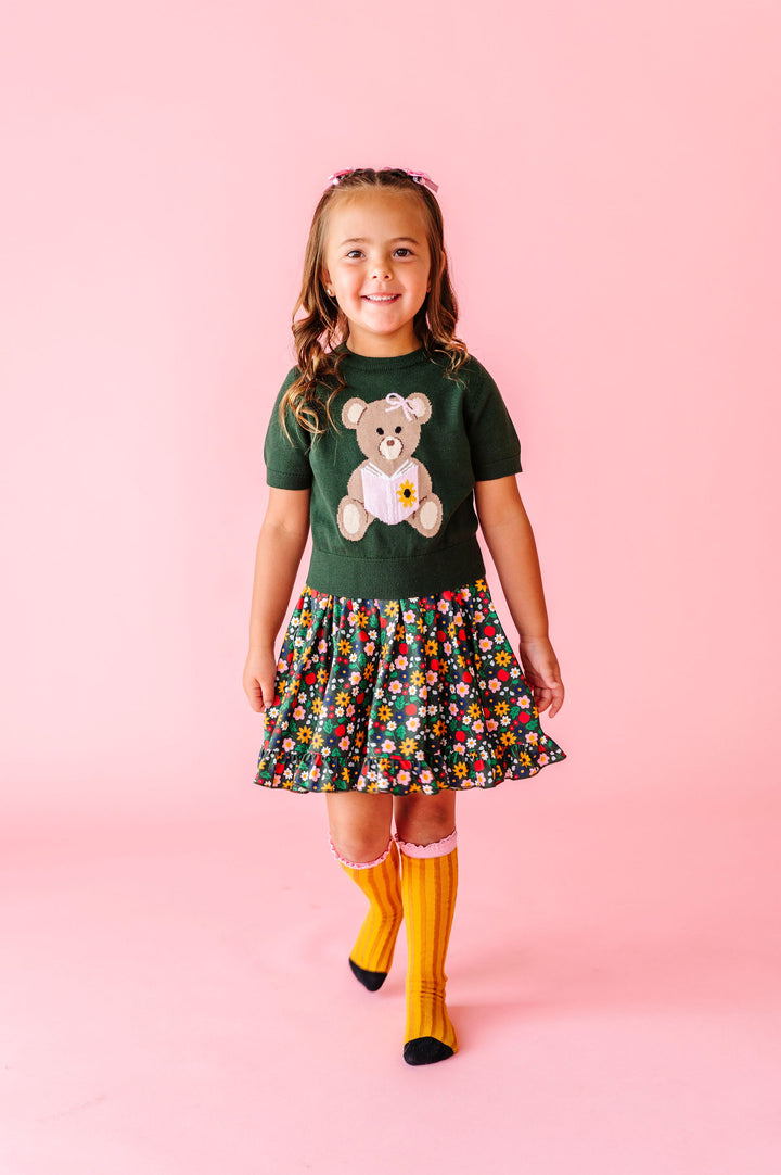 girl wearing reading bear sweater over back to school flower dress 