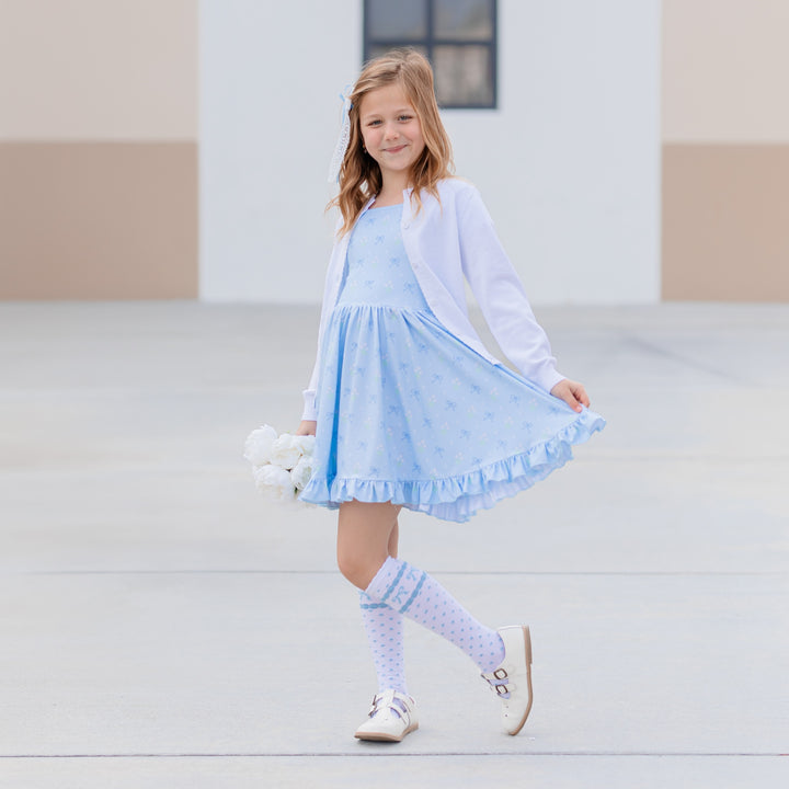 girl in blue floral square neck dress with matching white accessories and knee highs with blue bow print