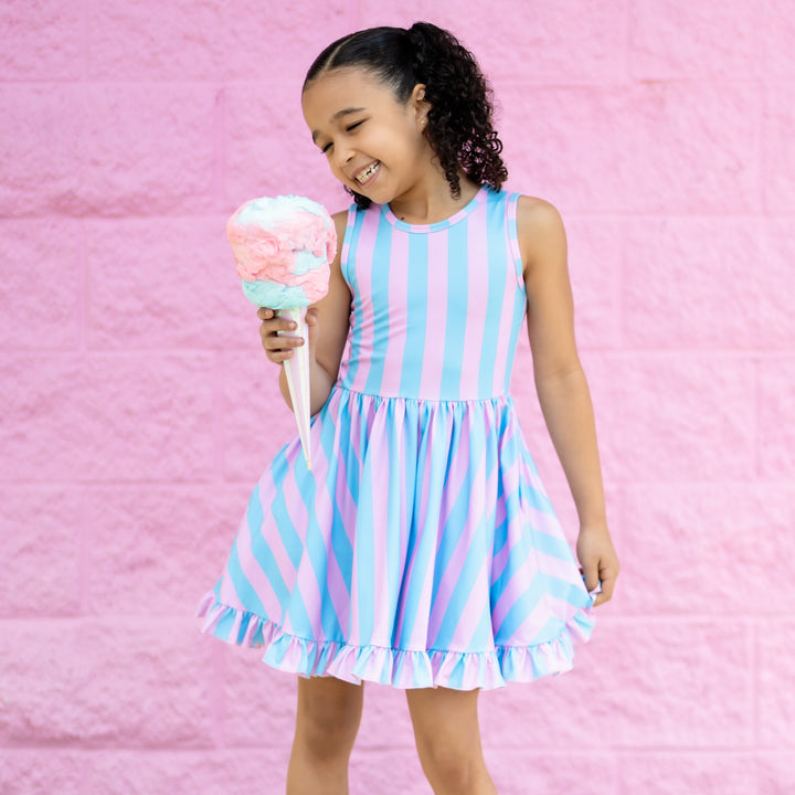 little girl eating cotton candy wearing a light blue and pink vertical striped summer dress