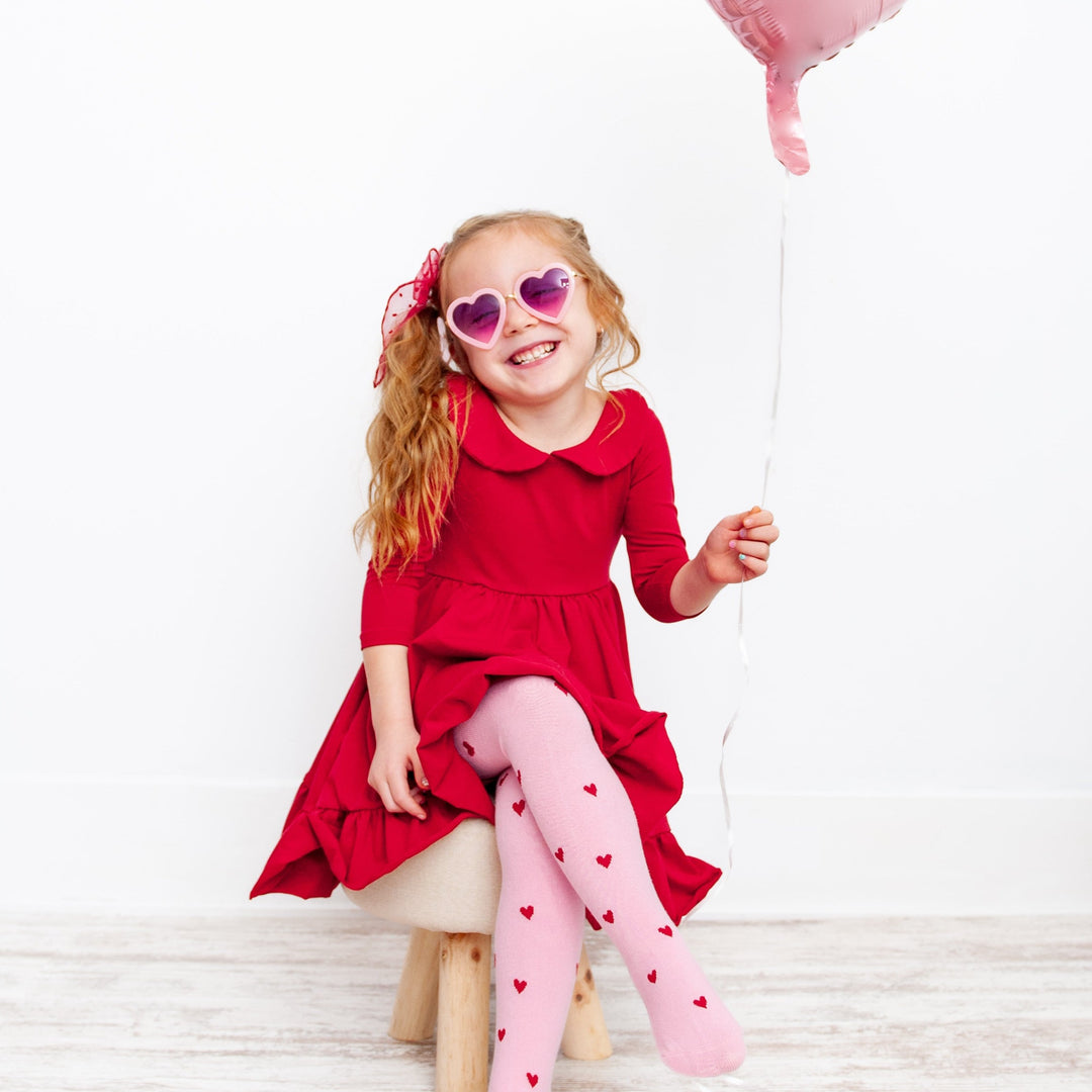 little girl in valentines red twirl dress with heart cotton tights