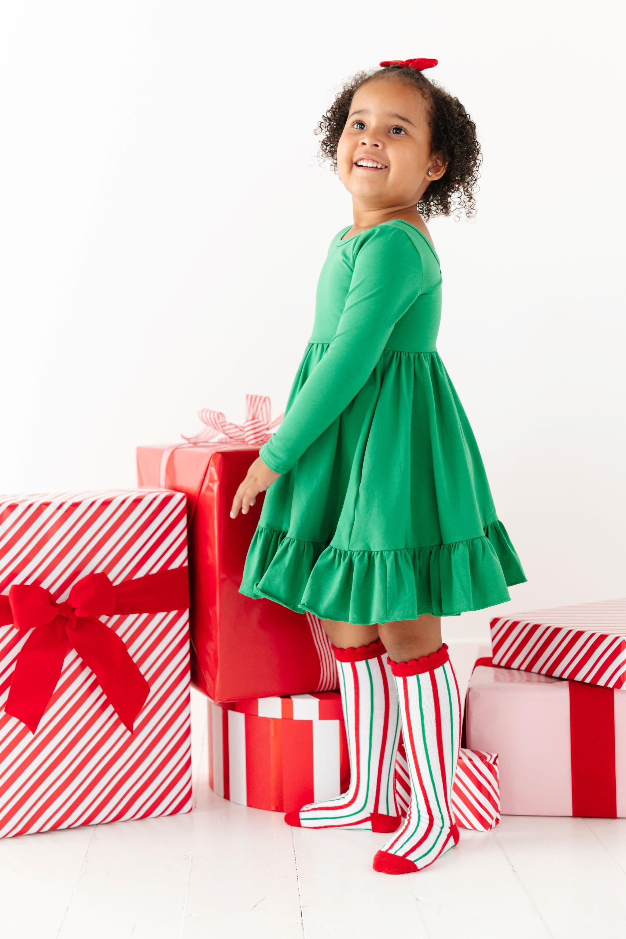 little girl in bright green holiday twirl dress with matching candy cane striped socks