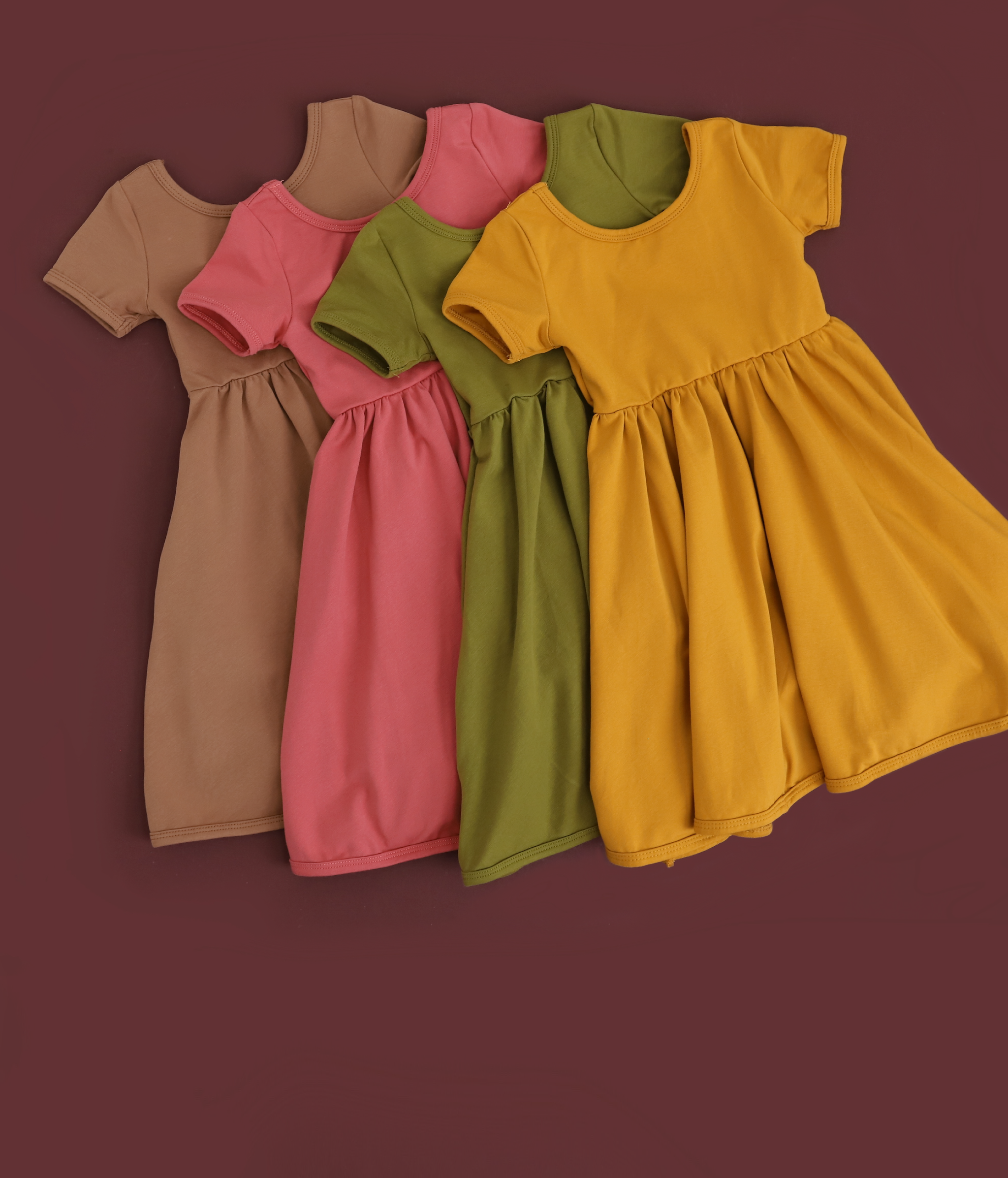 Flat lay of girls' everyday dresses in mocha, old rose, bright olive and mustard