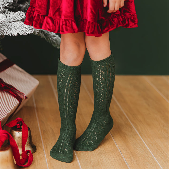 Girl wearing forest green pointelle knit socks with red velvet Christmas dress