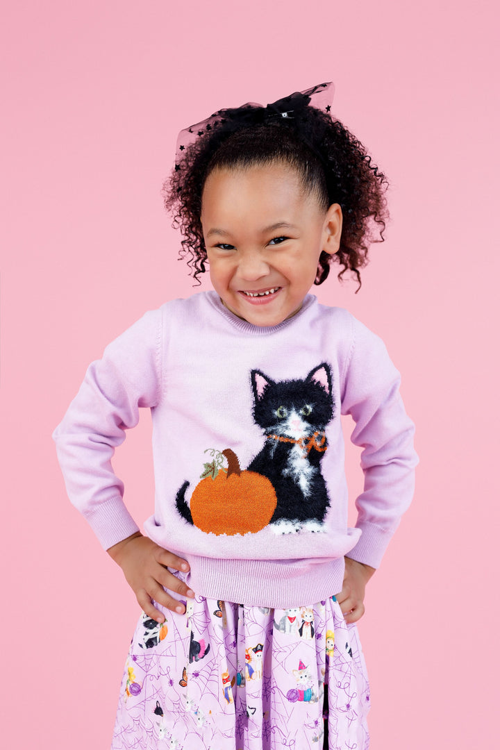 little girl in front on pink background wearing lavender cotton knit sweater with fluffy kitten and sparkly orange pumpkin design paired with matching lavender twirl dress with kittens in costumes