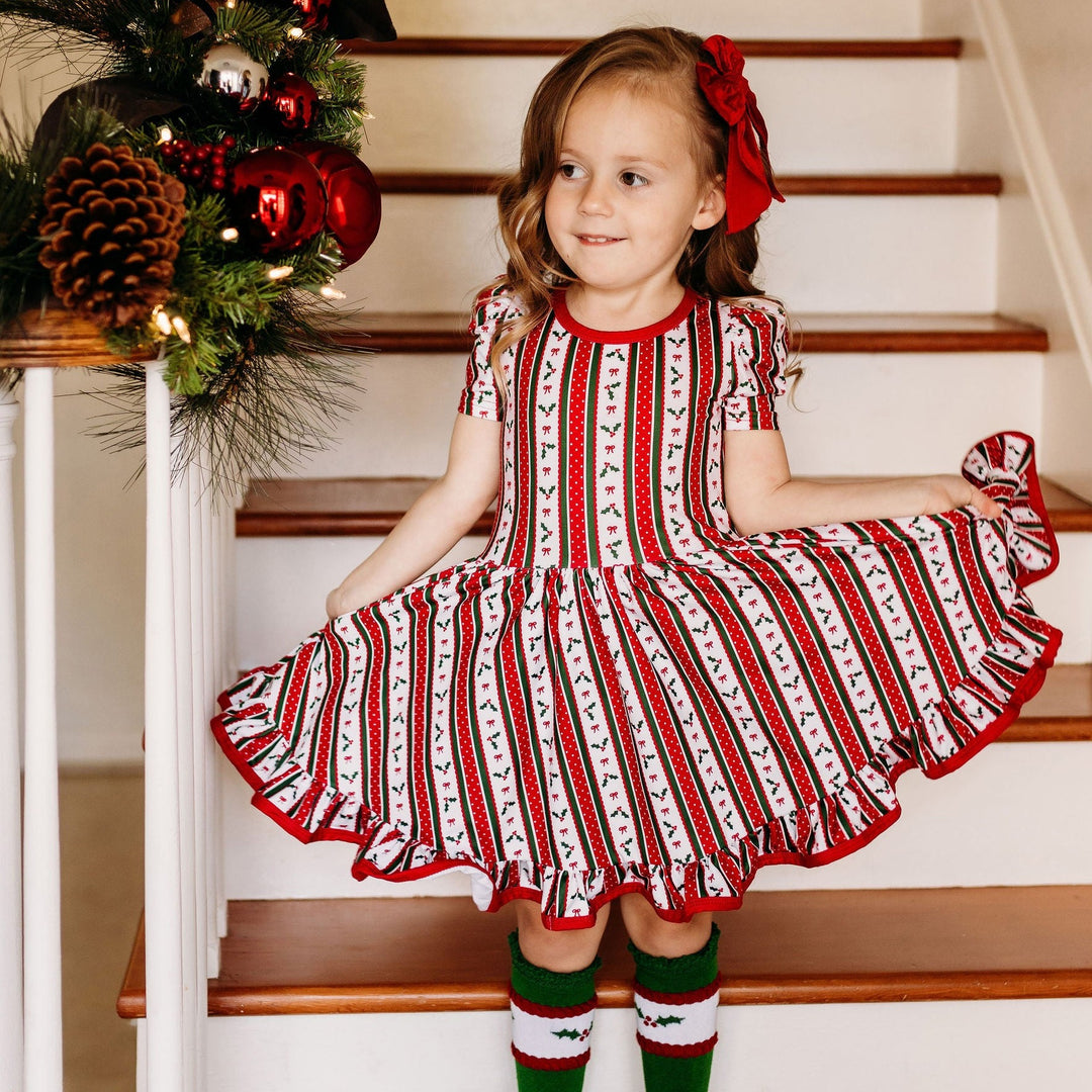 little girl wearing holly wallpaper christmas twirl dress
