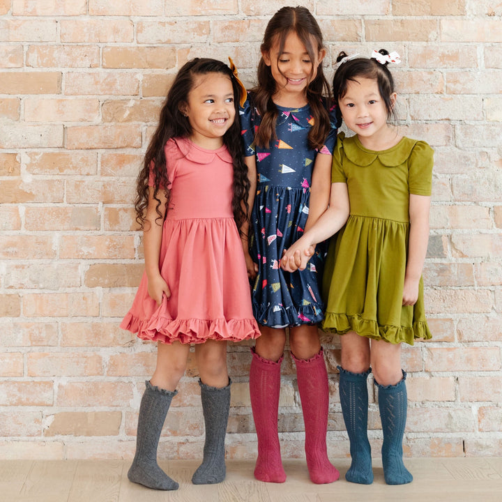 three little girls wearing gray, pink and blue mesh knee high socks with twirl dresses