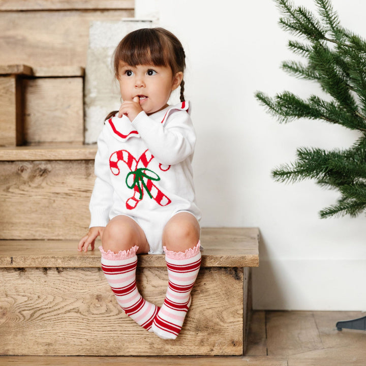 baby girl in christmas knit romper with candy canes and striped knee high socks