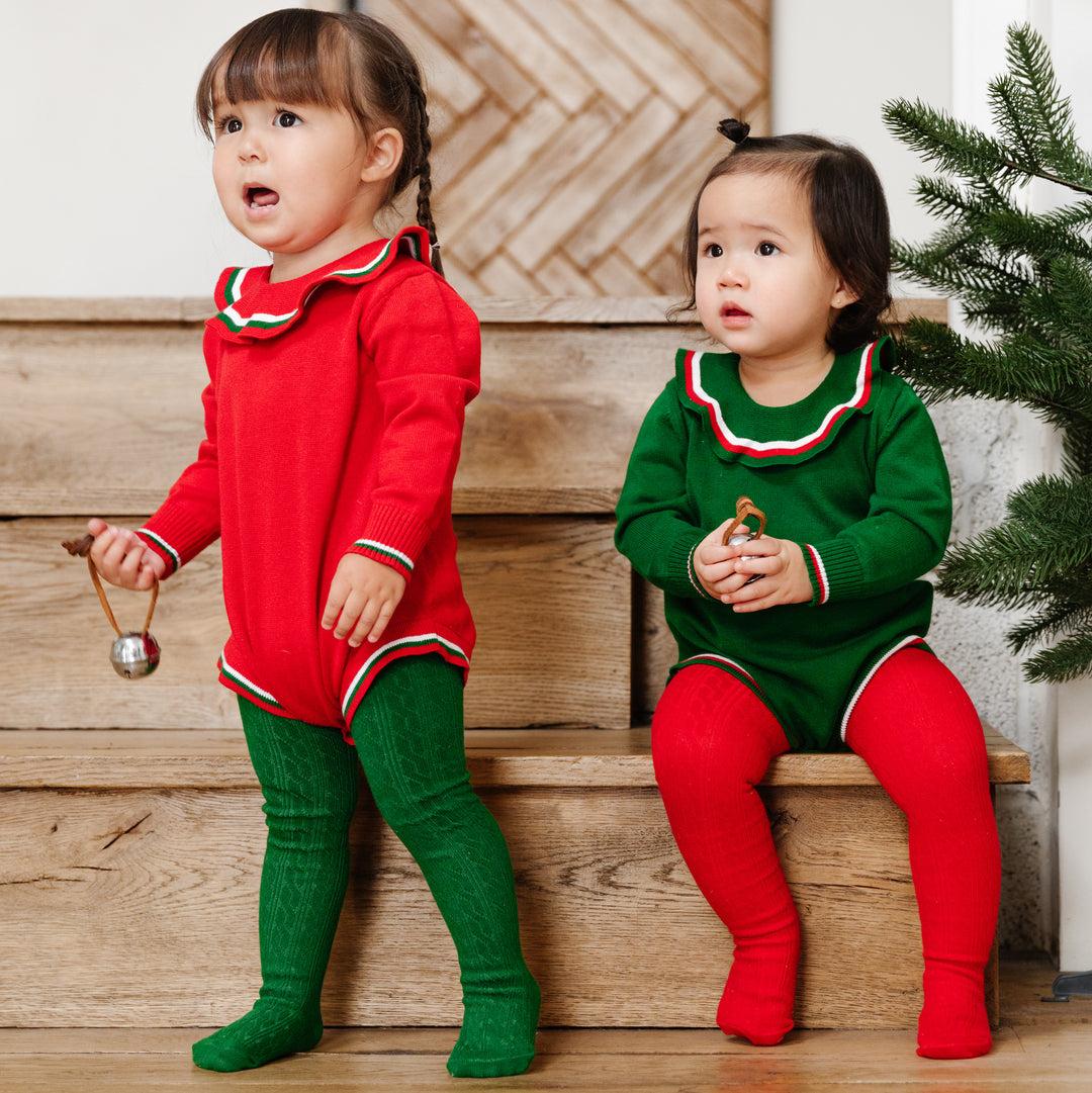 two toddler girls wearing coordinated christmas sweater bubble rompers and cute green and red christmas tights for girls