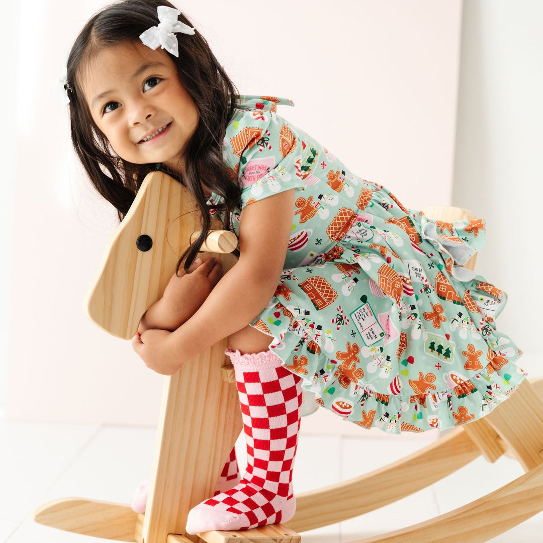 little girl wearing pink and red checker knee high socks with mint christmas twirl dress