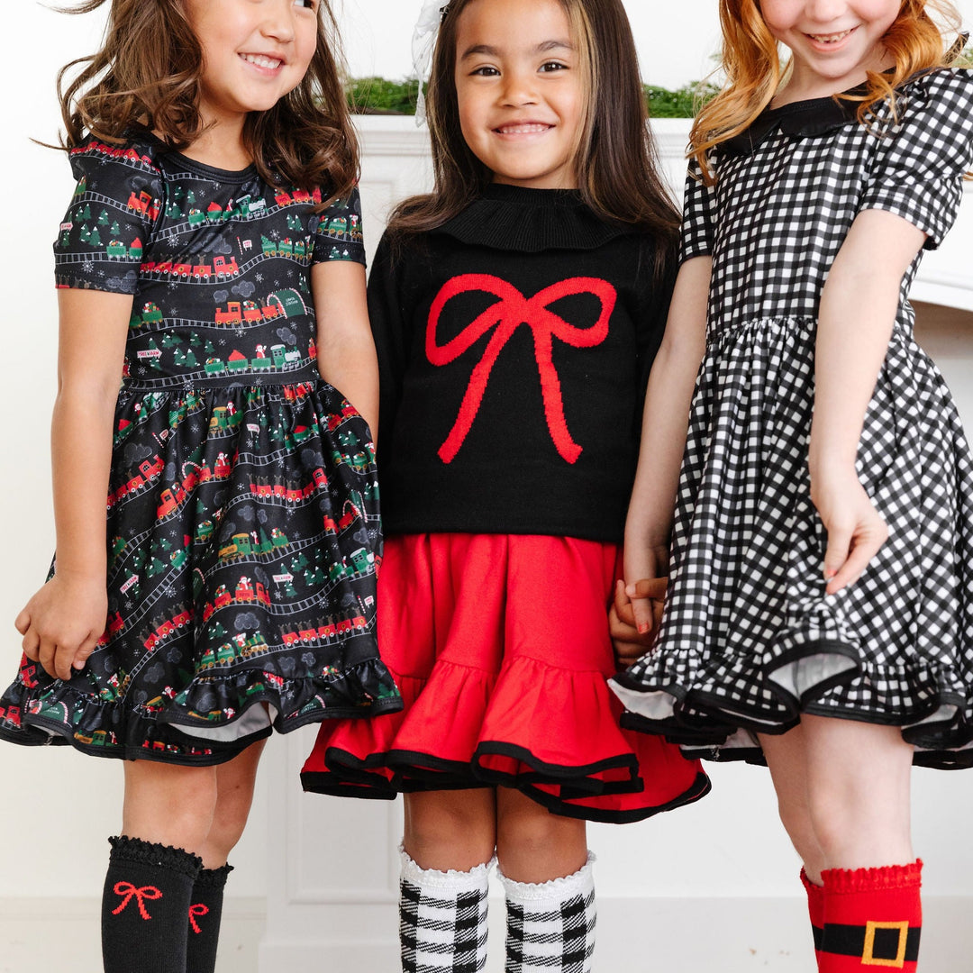 little girls wearing black and red christmas dresses with matching knee high socks
