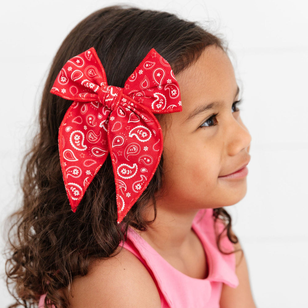 little girl in pink dress wearing red paisley print hair bow