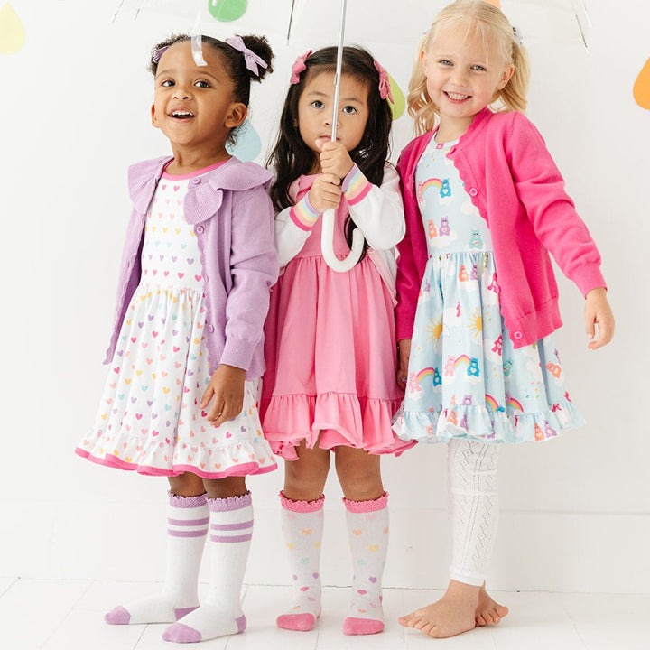 little girls wearing rainbow hearts and rainbow bear dresses with matching knee high socks and sweaters