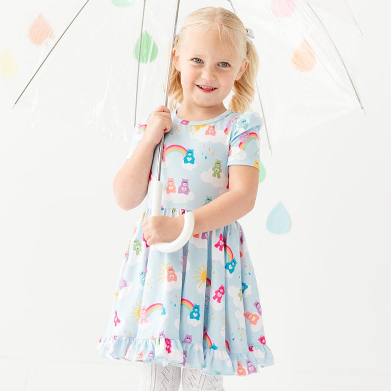 little girl wearing care bear inspired dress with rainbows and colorful bears
